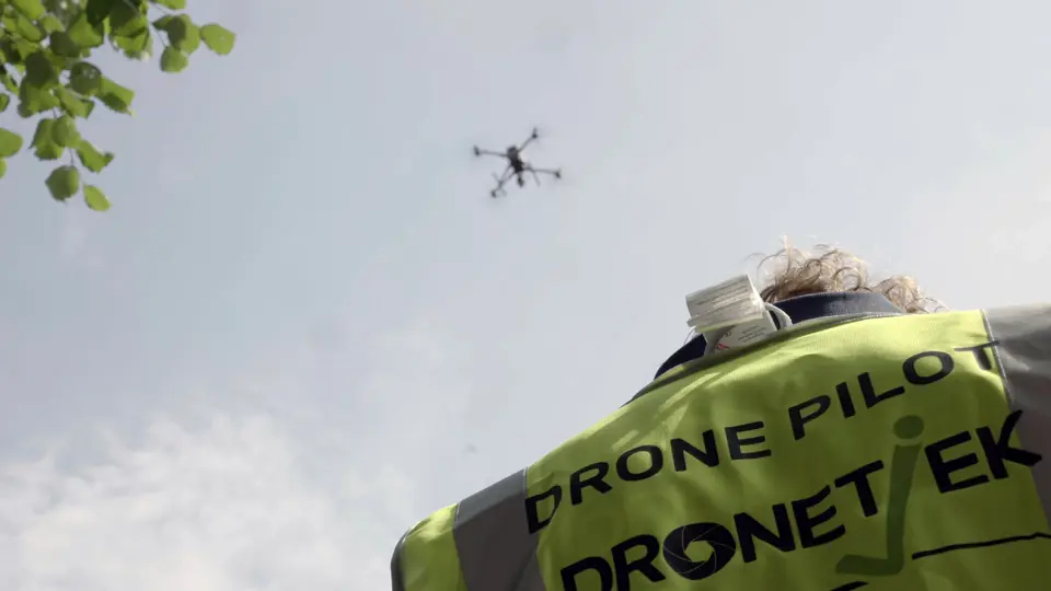 Drone I Luften Og Mand Med Arbejdstrøje Med Dronelogo