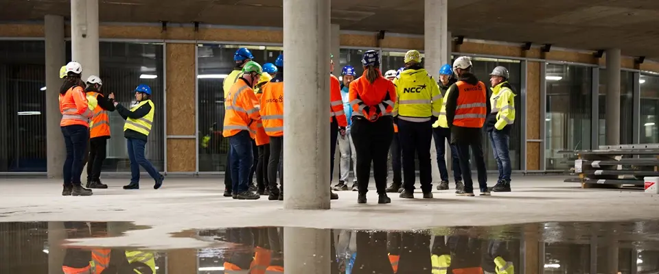 NCC Mænd Og Andre Arbejdsmænd I Et Rum Med Store Stolper